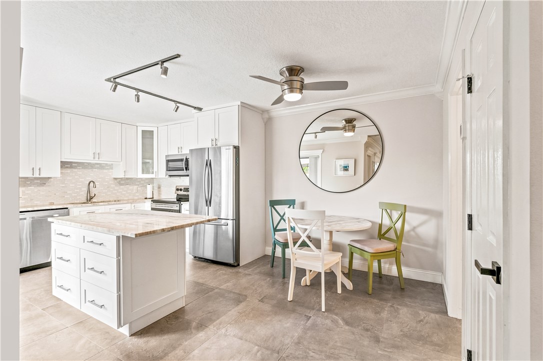 Kitchen featuring white cabinetry, stainless steel appliances, a kitchen island with stone countertop, and tile flooring