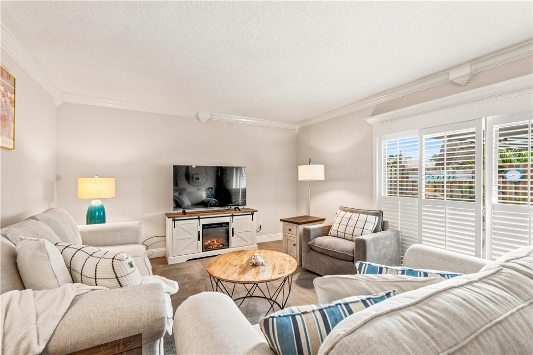 Spacious living area featuring crown molding, neutral wall tones, and wood-finish flooring