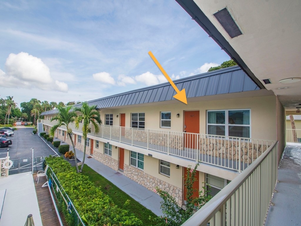 Exterior facade featuring a standing-seam metal roof, stone masonry accents, a private balcony with metal railing, and aluminum-frame windows