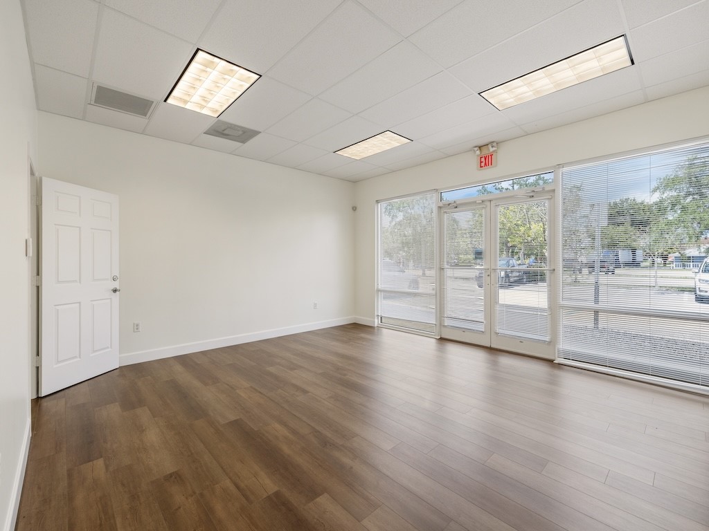 Wood-finish flooring, drop ceiling with recessed lighting, full-light entry doors, and large storefront windows