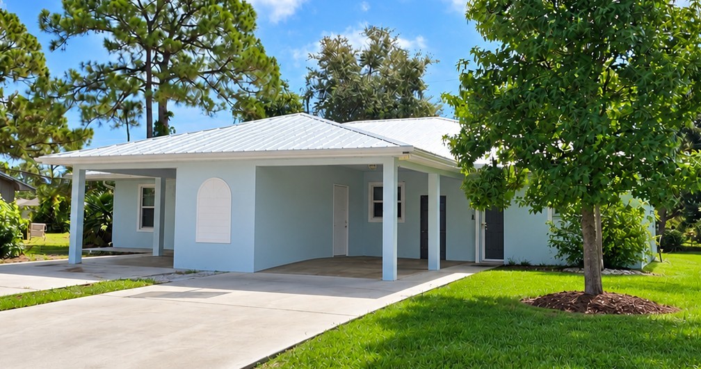 Light blue exterior with white trim, metal roof, and a covered carport