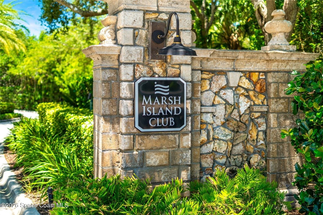 Stone entrance monument featuring a decorative wall sconce and integrated signage