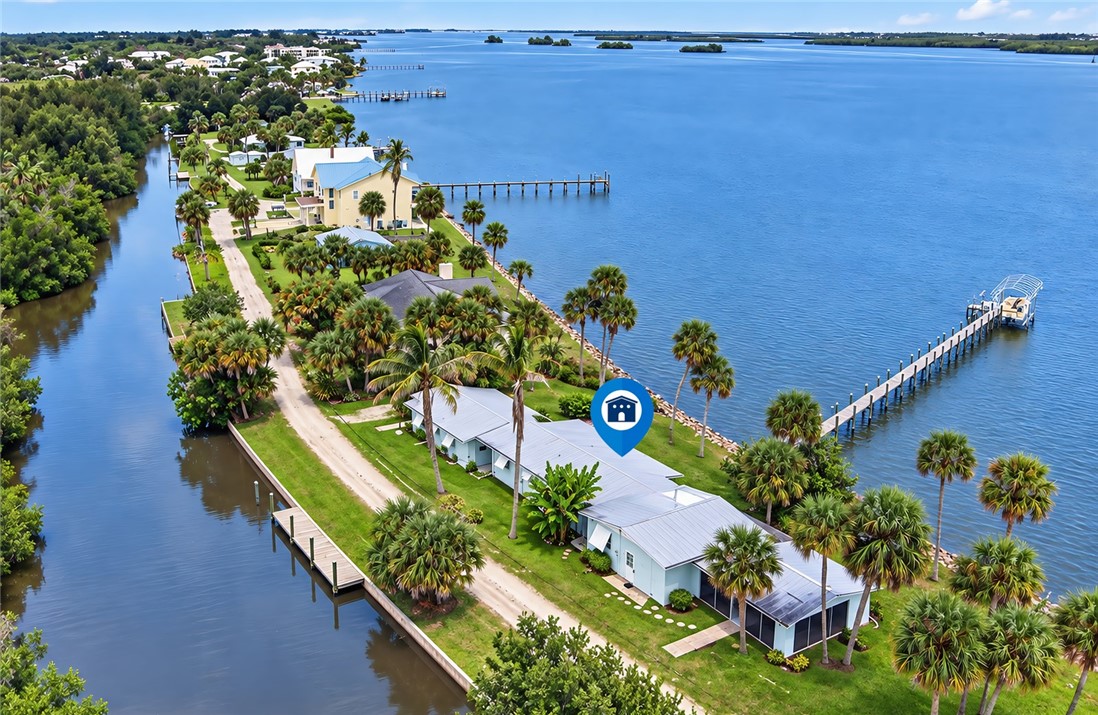 Waterfront property featuring a private boat dock, extended pier, and mature palm trees
