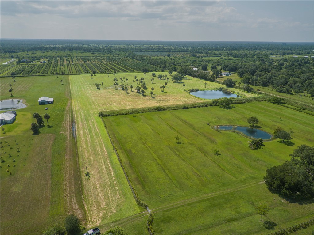 Expansive acreage featuring a pond, mature trees, and agricultural fields