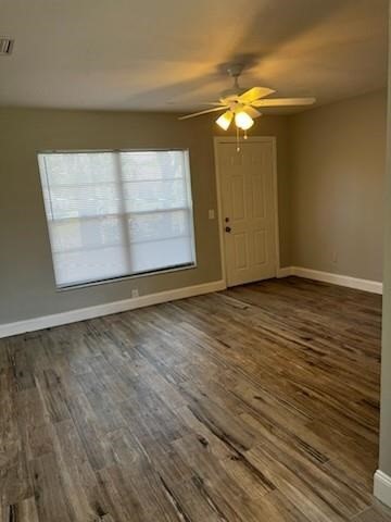 Spacious room featuring wood-finish flooring, a large window with blinds, and a ceiling fan with integrated lighting