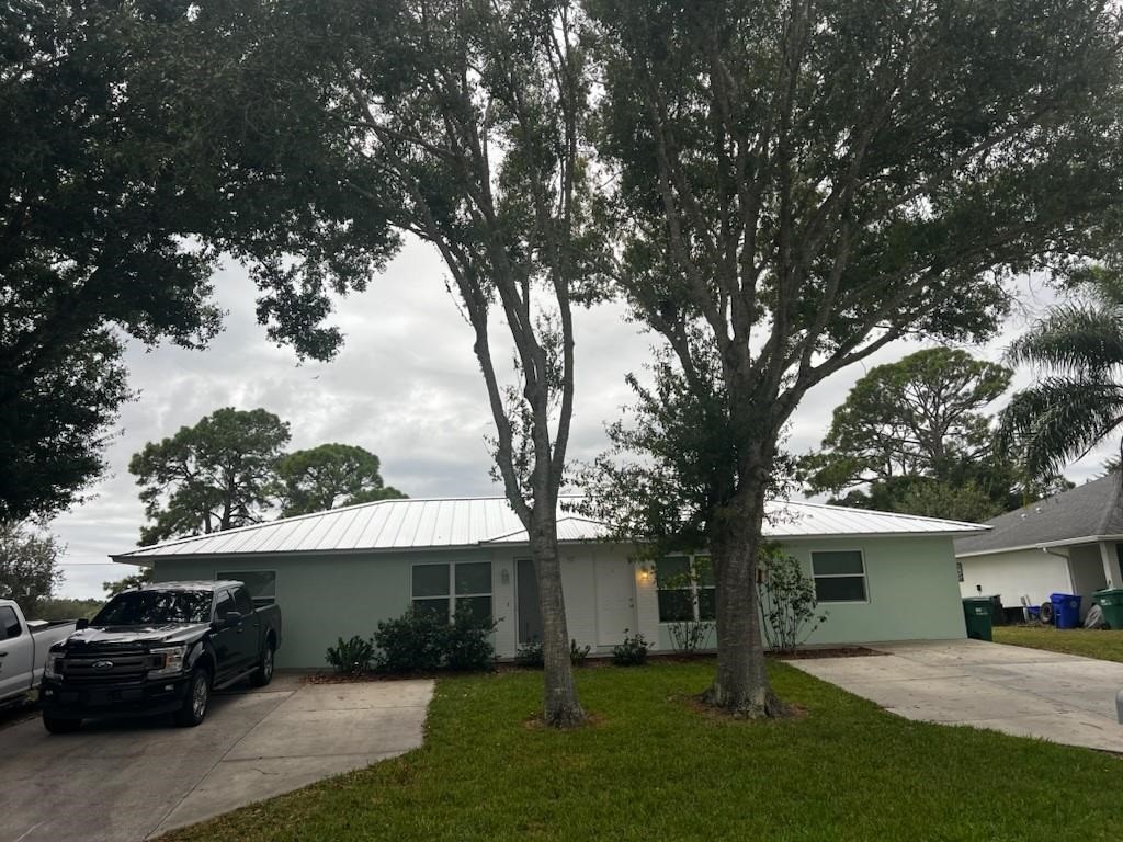 Single-story residence featuring a light-colored metal roof and a pale green exterior