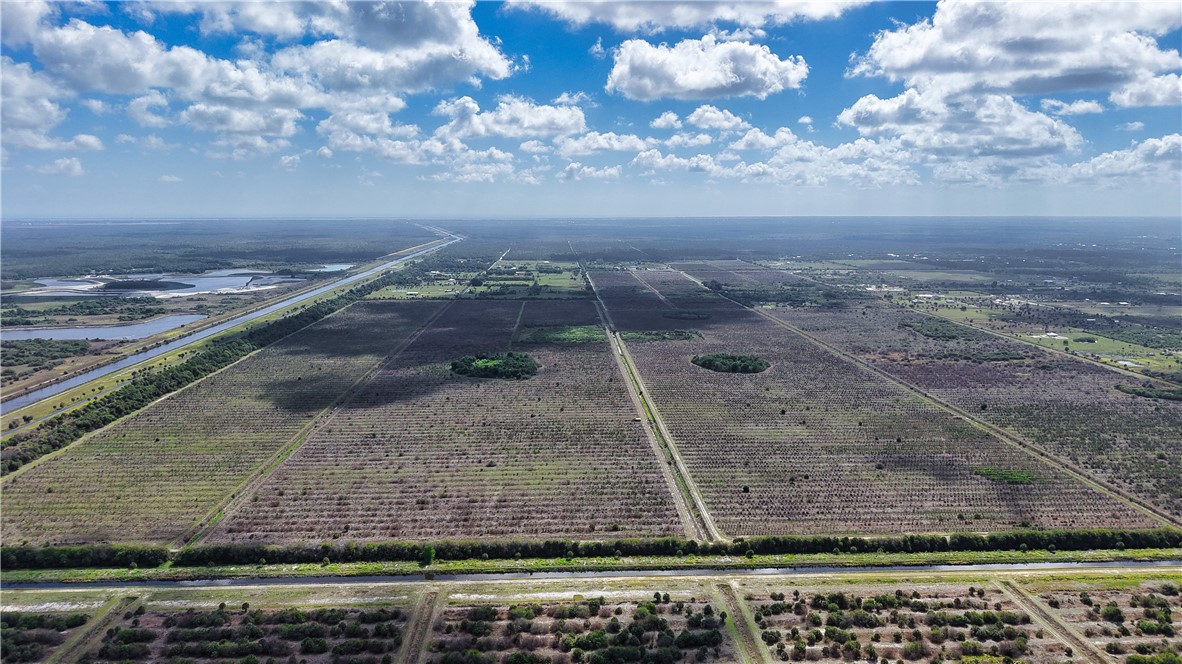 Expansive agricultural land featuring delineated parcels, a visible canal system, and distant water bodies