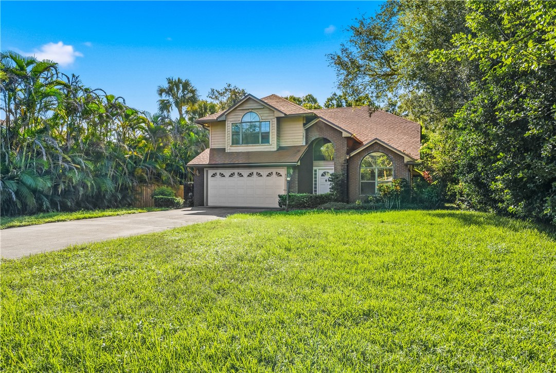 Two-story residence featuring a brick and siding exterior, an arched entryway, arched windows, and a multi-car garage