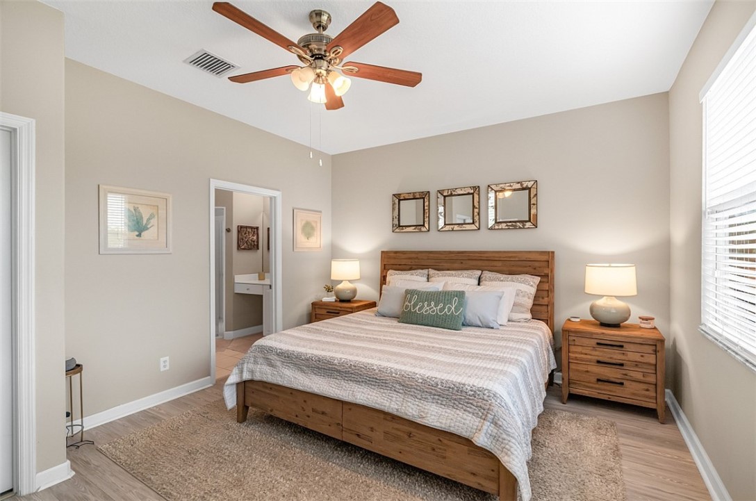 Bedroom featuring neutral wall paint, wood-finish flooring, and a multi-blade ceiling fan with integrated lighting
