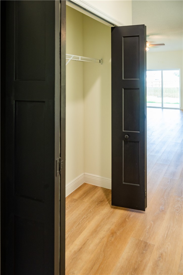 Closet featuring three-panel matte black doors, wood-finish flooring, and built-in wire shelving