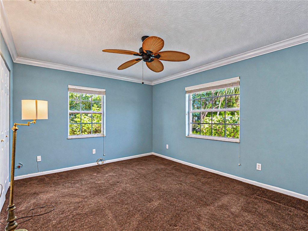 Room featuring crown molding, multi-pane windows, and a ceiling fan with woven-style blades