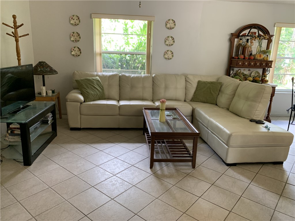 Ceramic tile flooring arranged in a diagonal pattern, dual windows with neutral-toned roller shades, and a recessed ceiling lighting fixture
