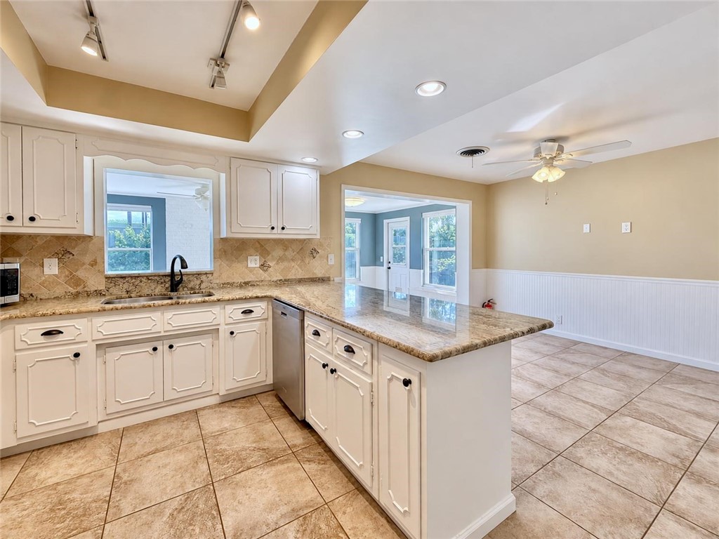 Kitchen featuring white cabinetry, stone-finish countertops, tile backsplash, tile flooring, and integrated ceiling track lighting