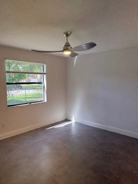Room featuring large-format ceramic tile flooring, neutral wall tones, and a modern three-blade ceiling fan with integrated lighting, featuring horizontal blinds