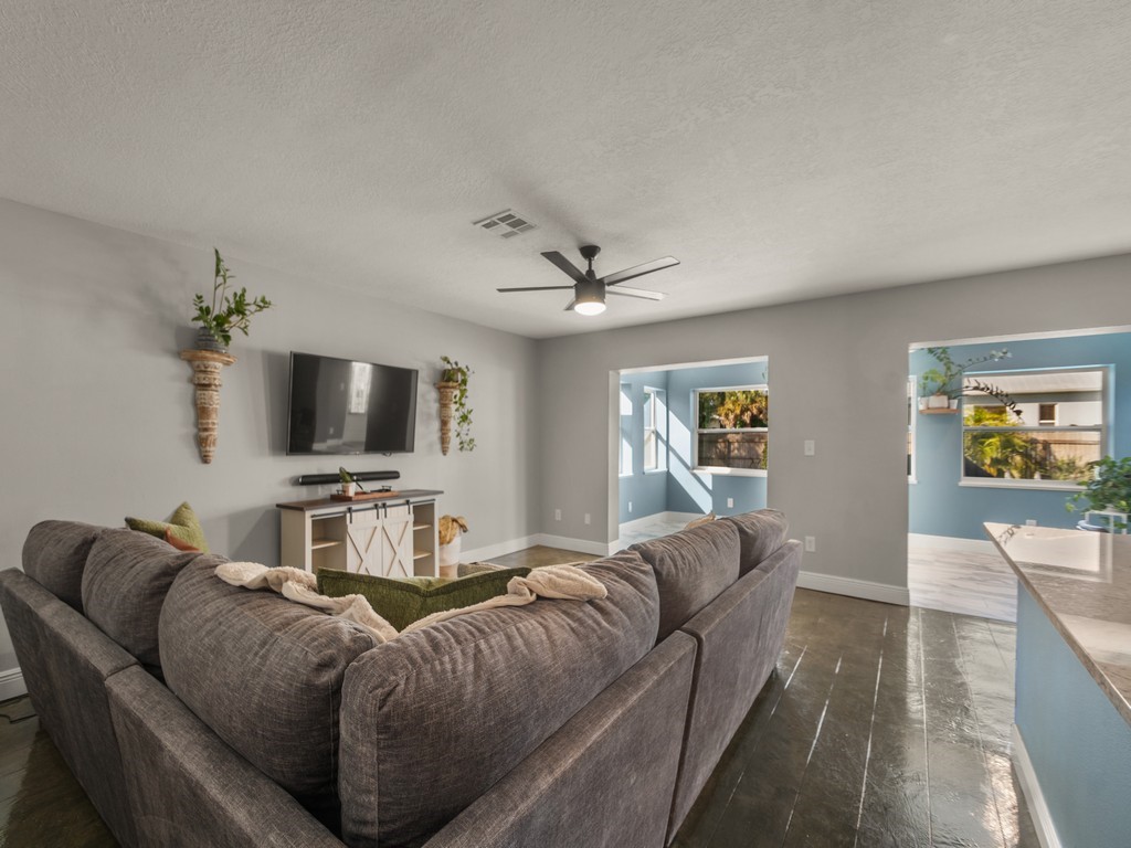 Interior space featuring dark-toned flooring, neutral wall paint, and a multi-blade ceiling fan with integrated lighting