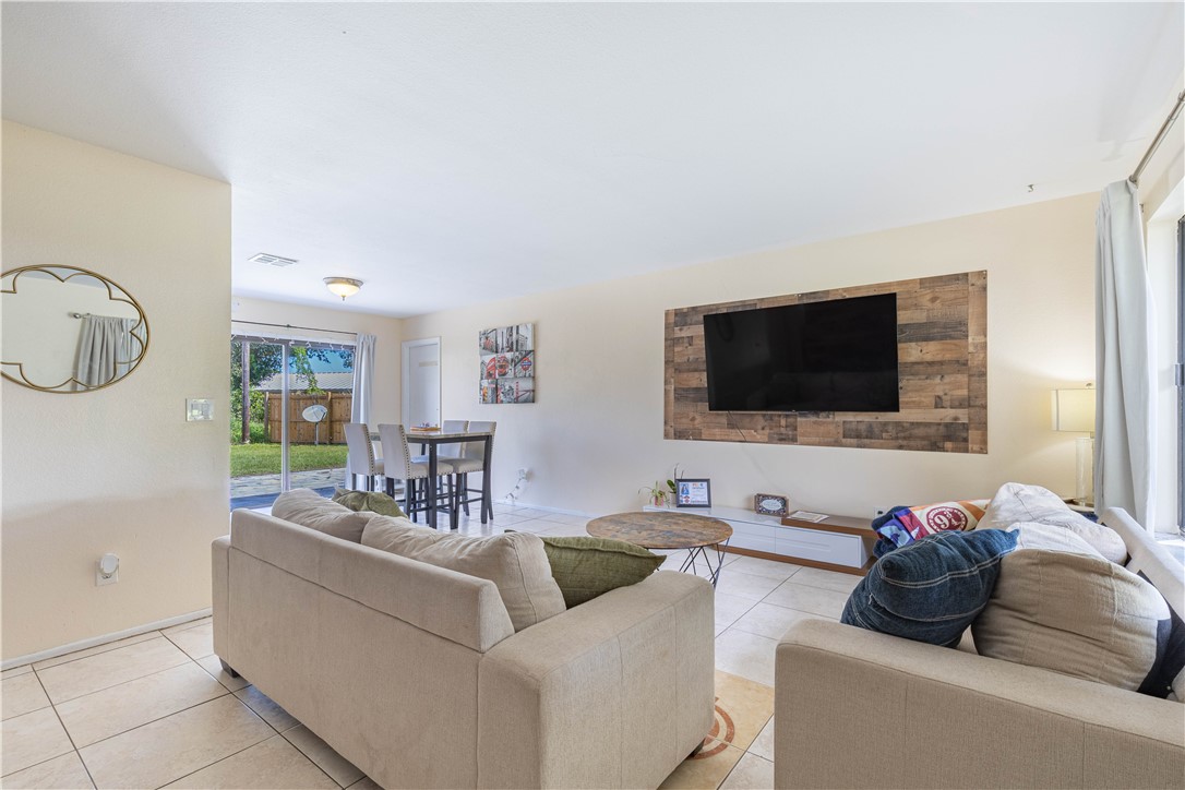 Neutral-toned tile flooring, wood-plank decorative wall accent, and sliding glass door leading to the exterior