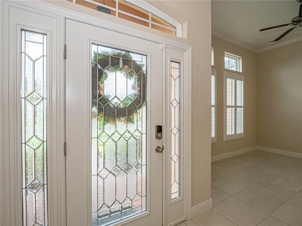 Entryway featuring crown molding, light tile patterned floors, and ceiling fan