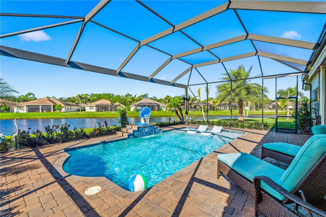 Screen-enclosed pool area featuring brick paver hardscaping, a raised water feature, integrated sun shelf, and water frontage