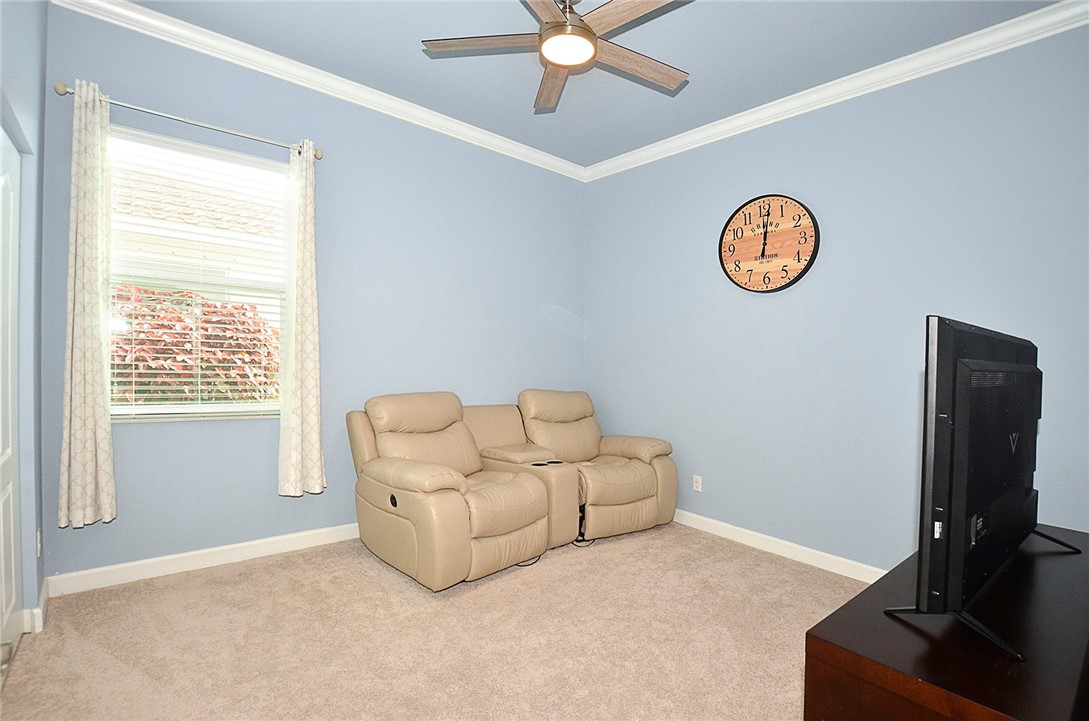 Room featuring neutral carpeting, crown molding, and a ceiling fan with integrated lighting