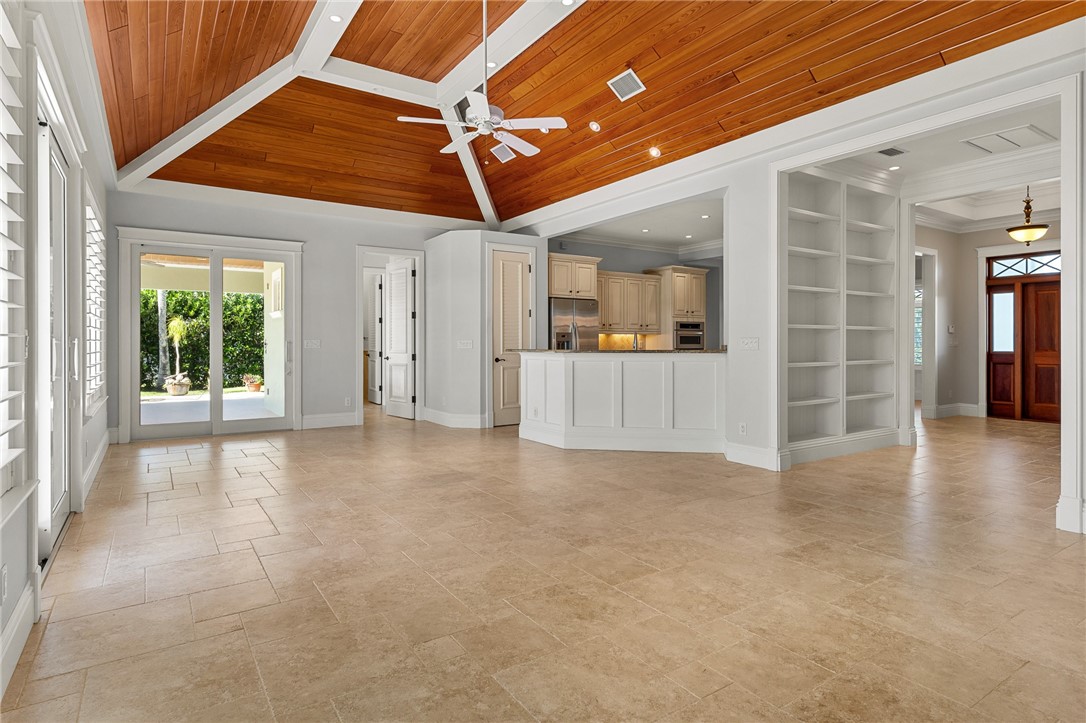 Vaulted ceilings with wood-plank detailing, tile flooring, built-in shelving, a kitchen peninsula with cabinetry, and glass sliding doors