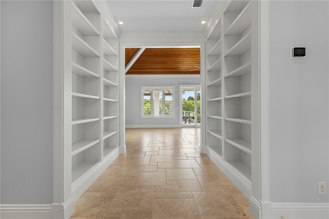 Passageway featuring floor-to-ceiling built-in white shelving, recessed lighting, tile flooring in a running bond pattern, and a high-pitched ceiling with wood-finish paneling