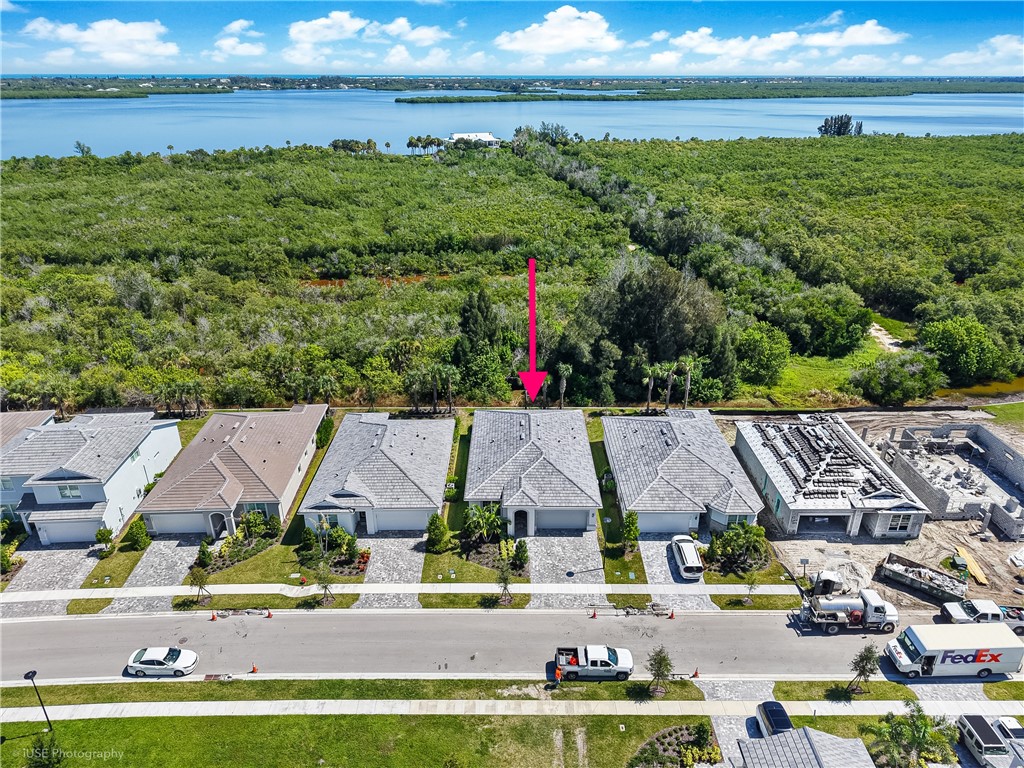 Single-story residence featuring a multi-gable roofline, attached two-car garage, paver driveway, and direct proximity to coastal water and native vegetation