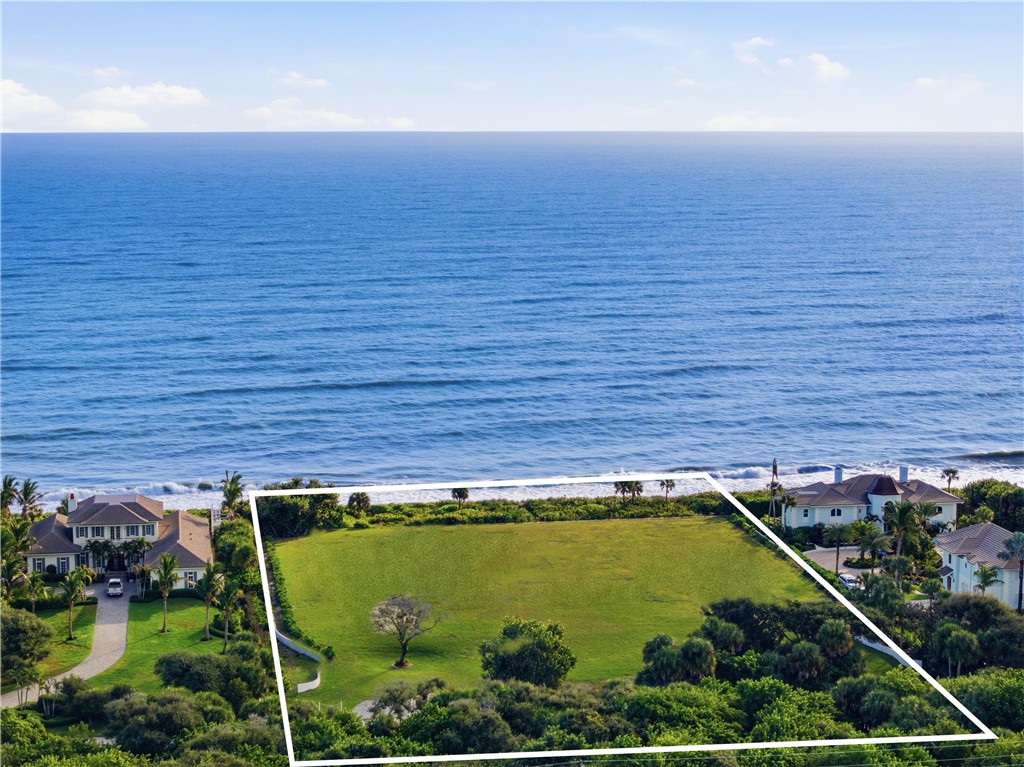 Direct oceanfront land parcel featuring an expansive cleared lawn, mature vegetation, and unobstructed coastal exposure