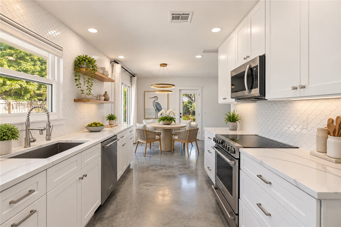 Virtually Staged - featuring white cabinetry, solid-surface countertops, scalloped tile backsplash, polished concrete flooring, and stainless steel appliances