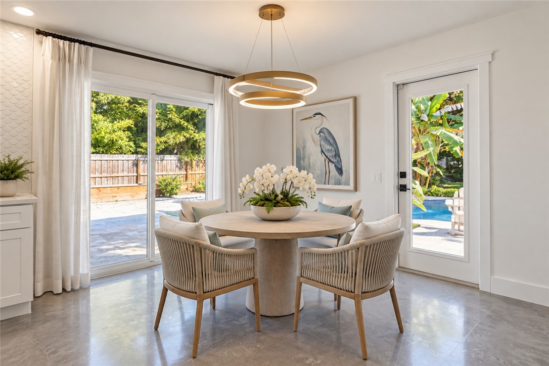  Virtually Staged - Polished concrete flooring, contemporary gold-tone ring chandelier, sliding glass patio doors, and full-glass exterior door