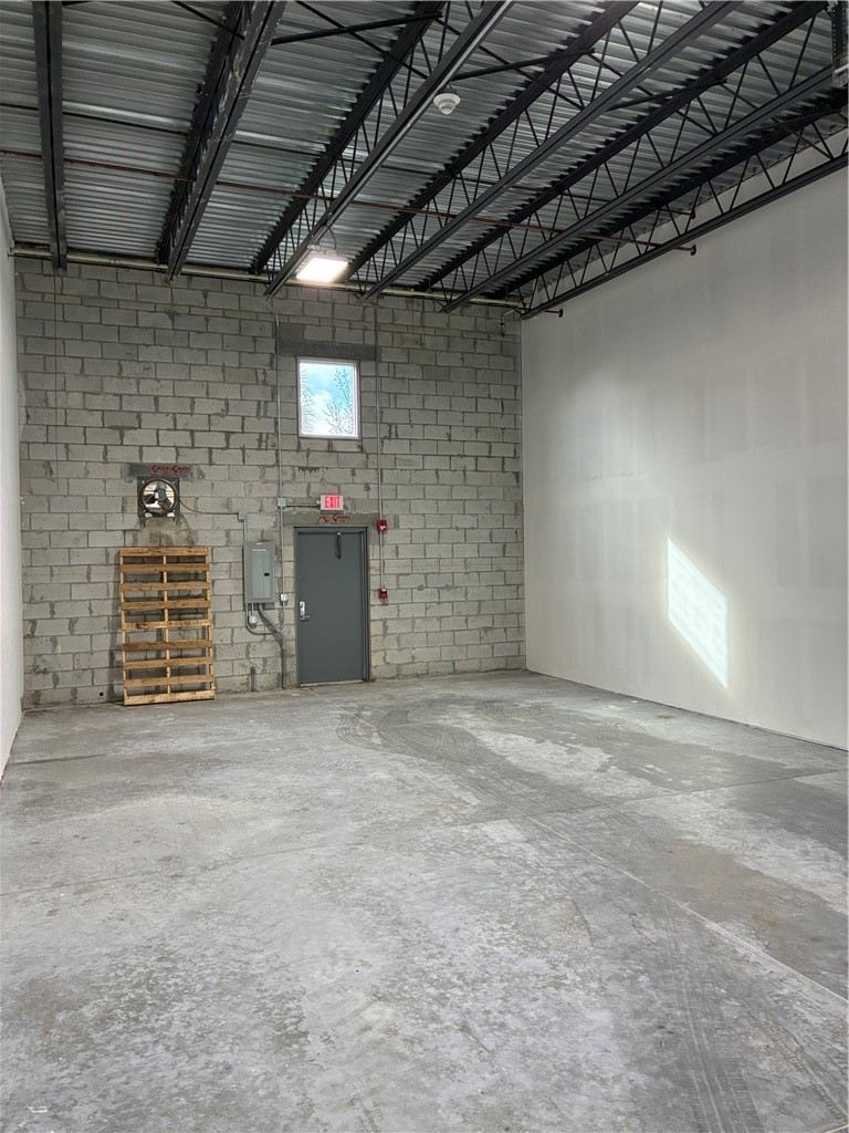 Industrial space featuring high-clearance open-web steel joists, exposed concrete block walls, painted drywall, and a durable concrete slab floor