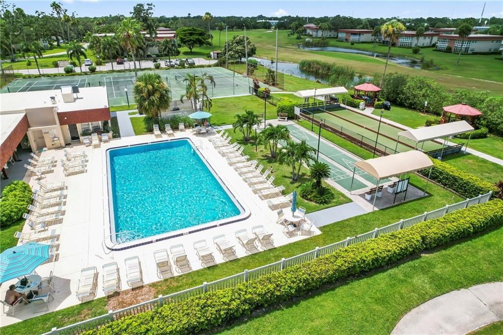 Recreational grounds featuring a swimming pool, tennis courts, and shuffleboard courts with shaded structures