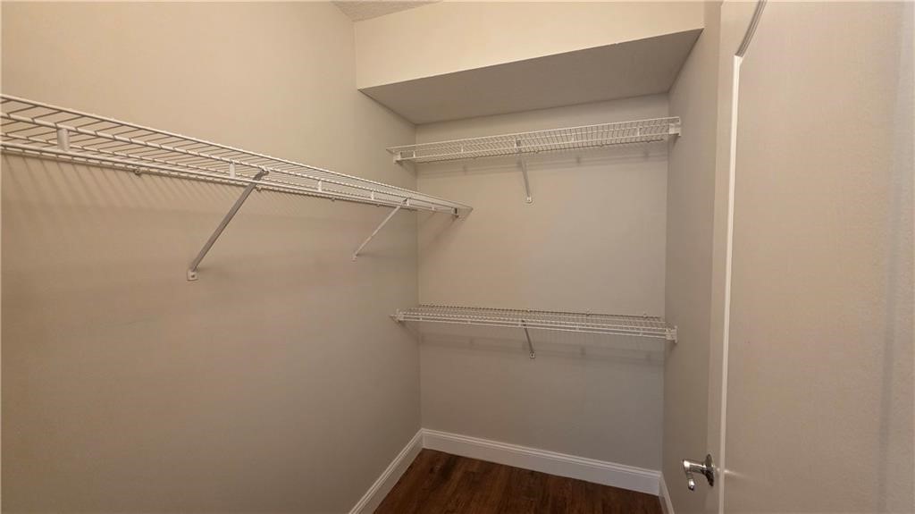Walk-in storage space featuring wood-finish flooring and multi-level white wire shelving