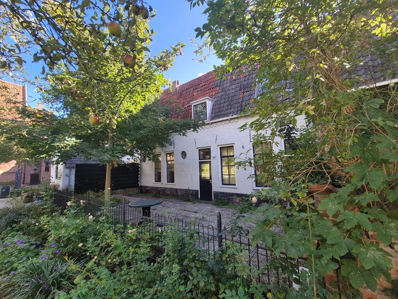 Wit geschilderde historische woning met voortuin na onderhoud van het schilderwerk