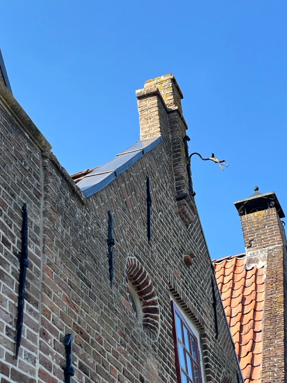 Historische bakstenen topgevel met nieuw loodwerk en smeedijzeren muurankers