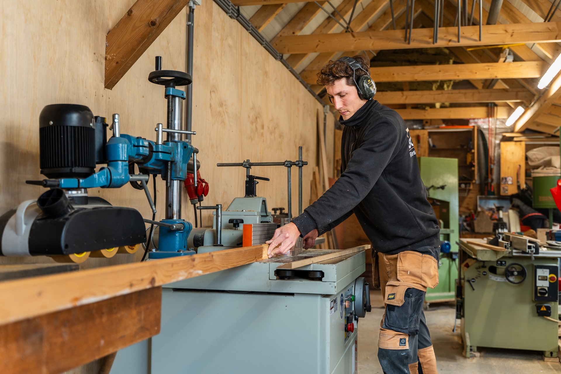 Vakman voert hout door de freesmachine in de machinale timmerwerkplaats