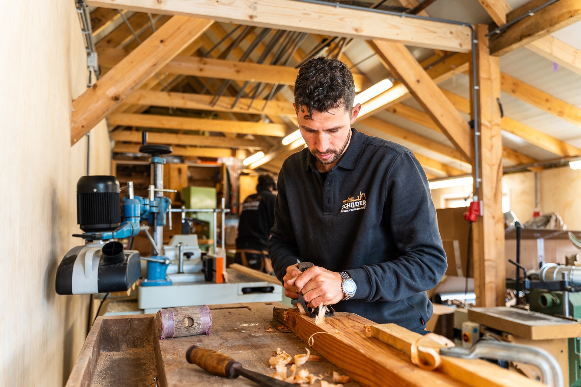 Vakman schaaft met een handschaaf een eiken balk in de machinale werkplaats