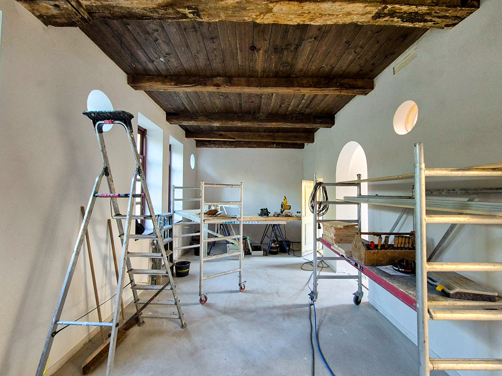 Interieur in restauratie met houten balkenplafond, steigers en ronde vensters