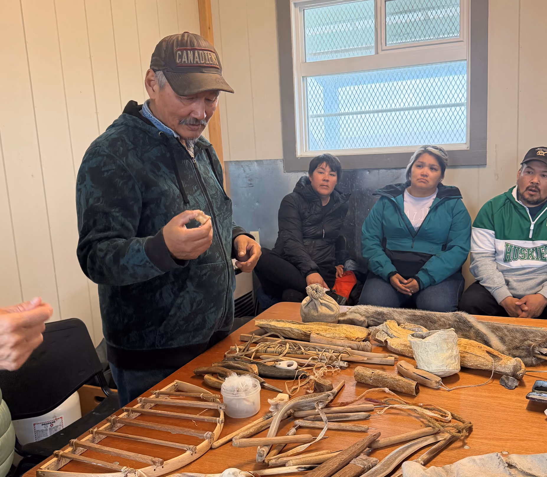 A man shows a group of people traditional tools on a table