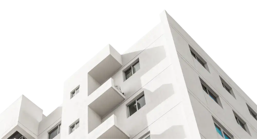 White multi-story building with small balconies and windows against a clear sky.