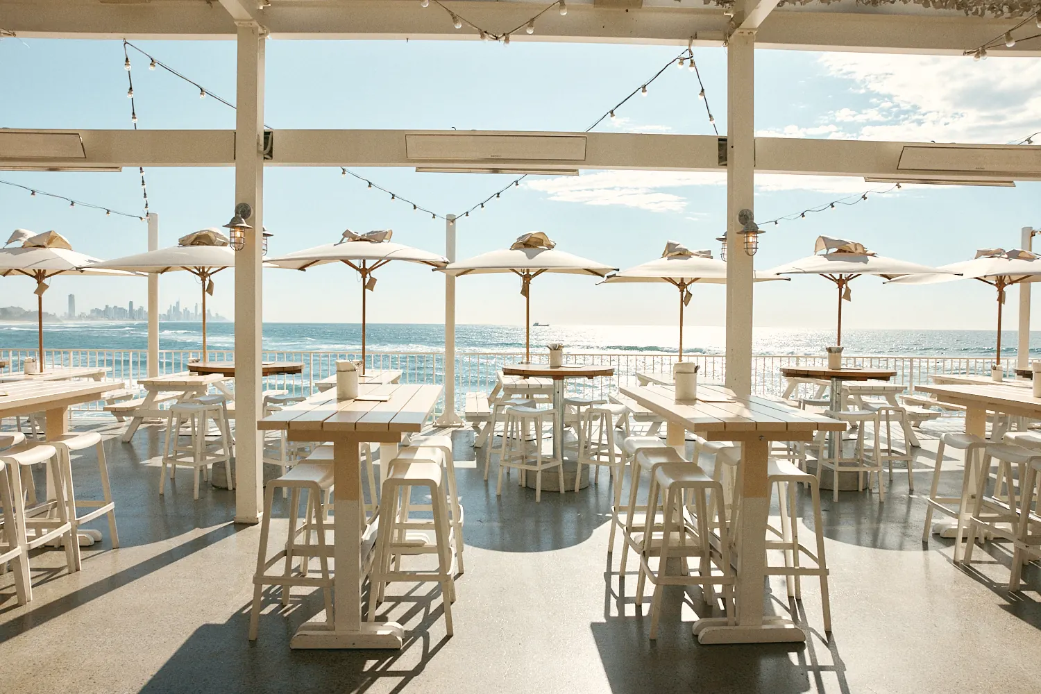 Terrace tables and white umbrellas at The Pav overlooking the ocean and Surfers Paradise skyline