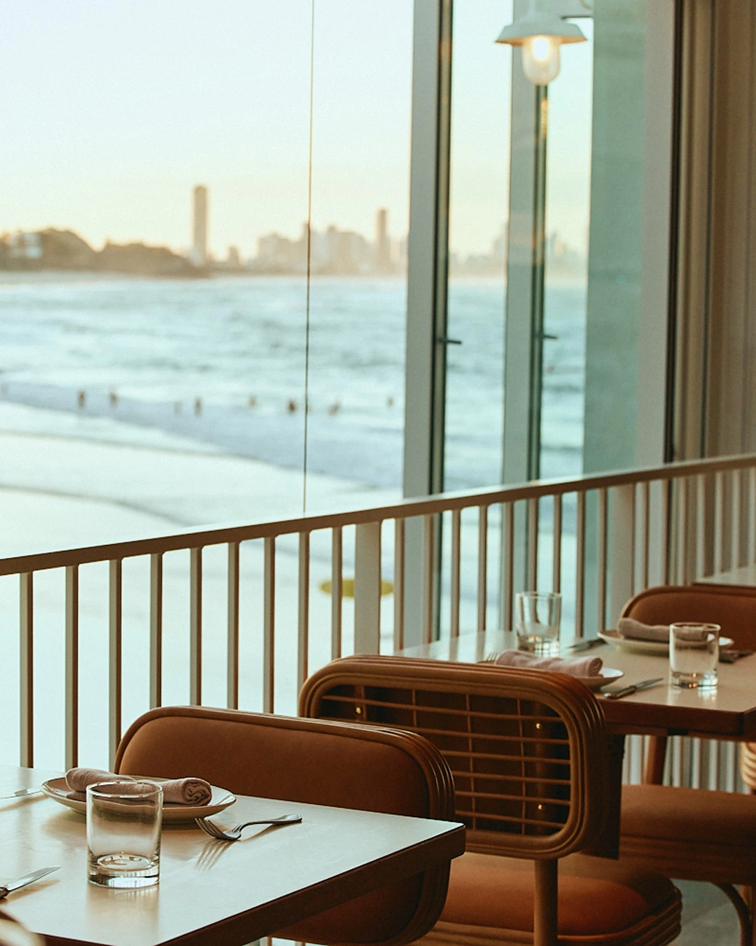 Rattan dining chairs at The Tropic overlooking the beach and Surfers Paradise skyline