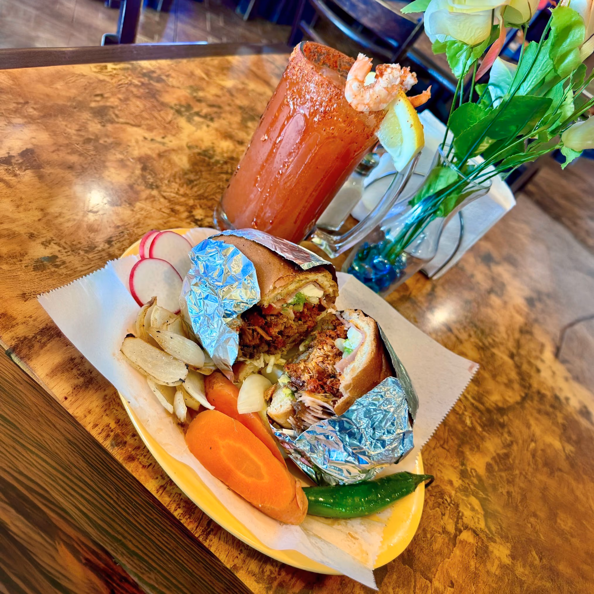 A Mexican al pastor torta with a michelada on the side.