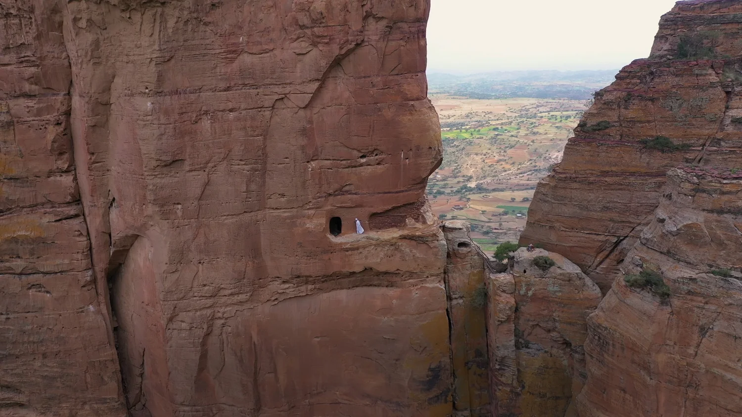 A rock-hewn church opens onto a narrow ledge above Ethiopia’s Tigray landscape.