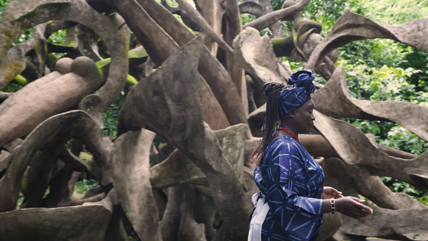 A woman in blue walks among sculptures at the Osun-Osogbo Sacred Grove in Nigeria.