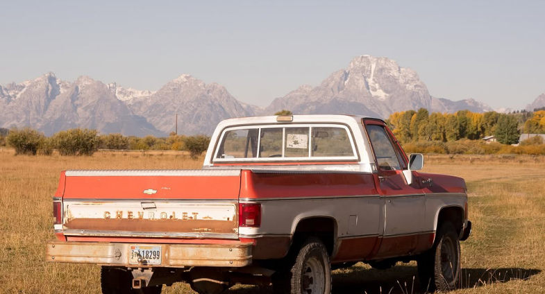 Red pickup truck in a mountain field
