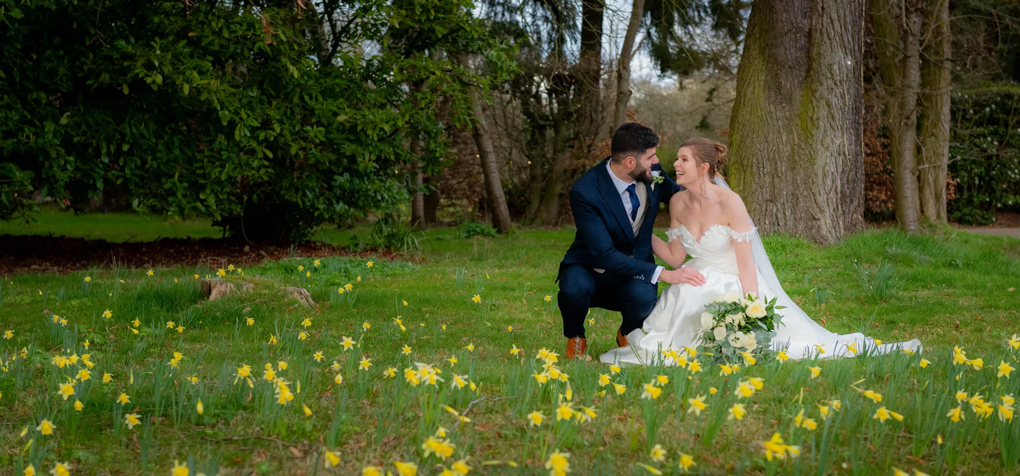A bride and groom among spring daffodils on the lawn at Lanwades Hall