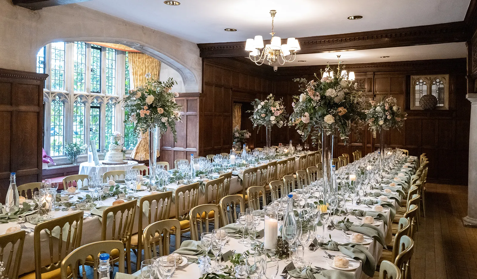 Long wedding breakfast tables beneath the leaded bay window in the Great Hall at Lanwades Hall