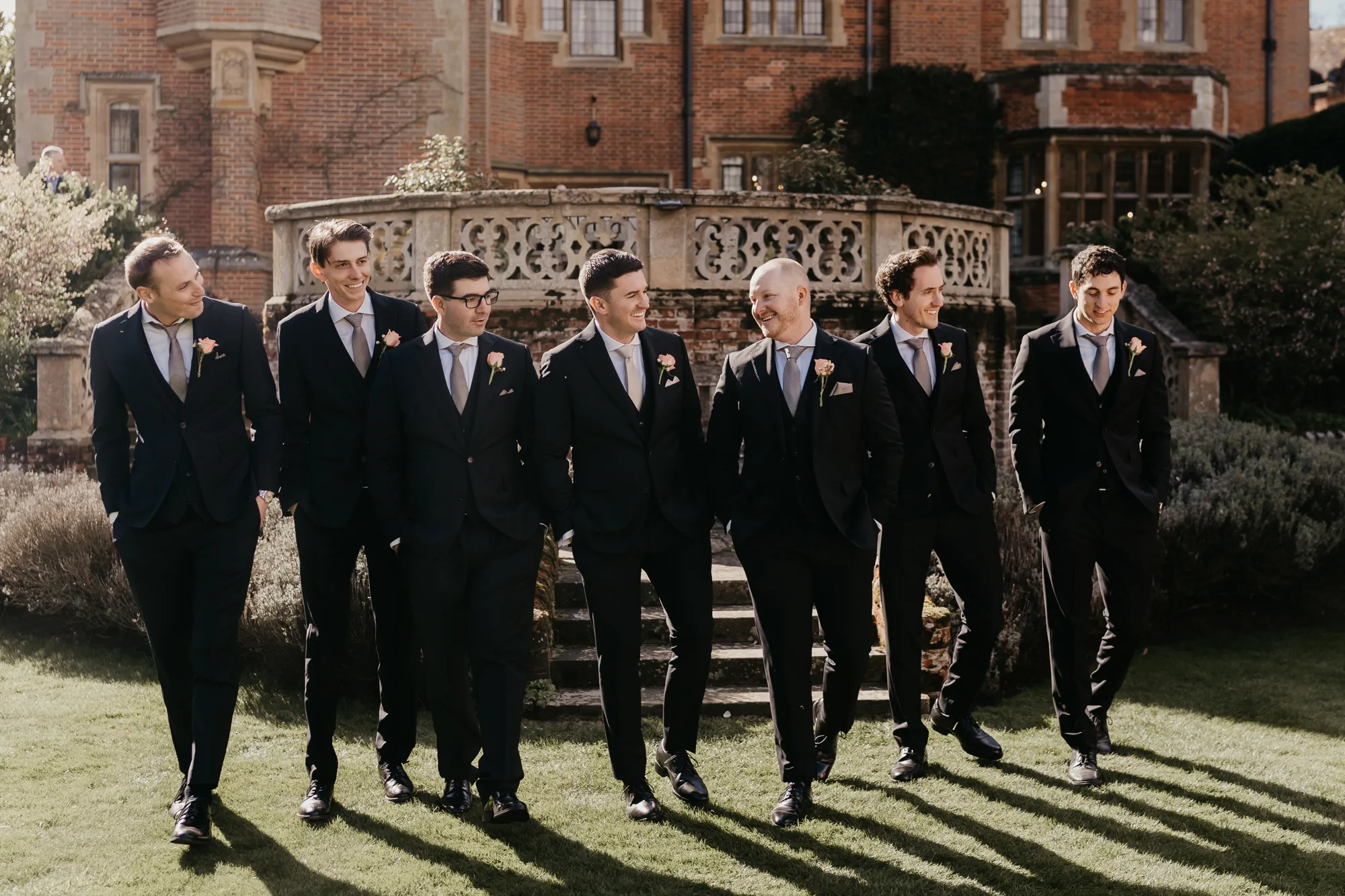 Groomsmen gathering on the lawn below the terrace on the wedding day at Lanwades Hall