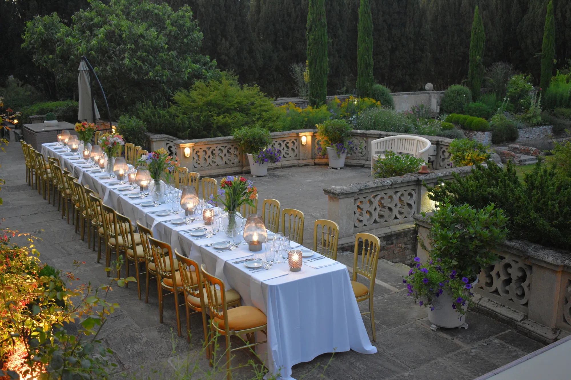 A candlelit dinner party on the terrace at dusk at Lanwades Hall