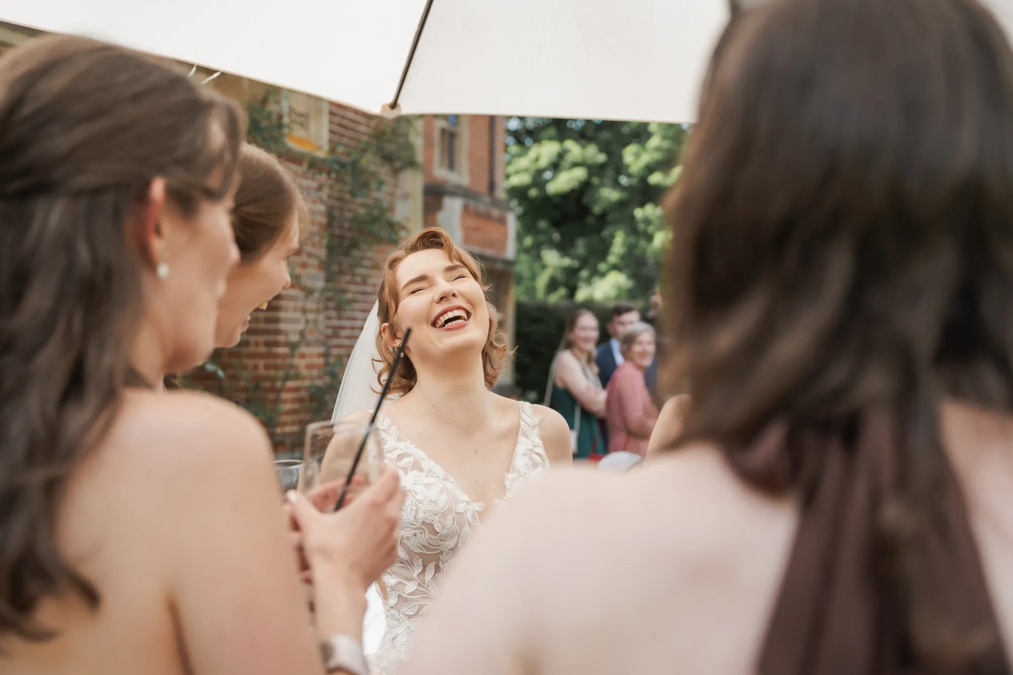 A bride laughing with friends during the drinks reception at Lanwades Hall